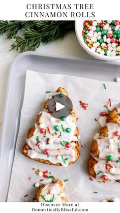 christmas tree cinnamon rolls with white frosting and sprinkles on a tray