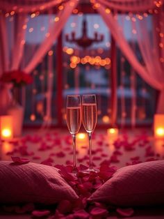 two glasses of champagne sitting on top of a bed with rose petals in front of a window