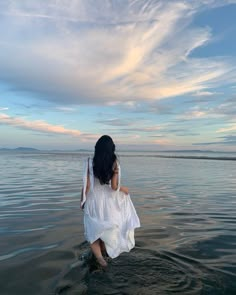 a woman sitting in the water looking at the sky