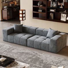 a large gray couch sitting on top of a living room floor next to a book shelf