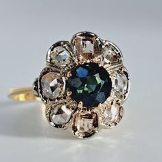 Beautiful antique natural diamond and sapphire halo ring in 18K yellow gold circa mid-18th century. This pretty ring features eight very high quality antique table and rose cut diamonds surrounding a round cut natura sapphire.  The diamonds vary in size, from  approximately 3.2 to 4mm each and a blue antique cut sapphire of 6.8mm. The diamonds and sapphire are in excellemt condition. No chips or cracks or significant scuffs. Ring size 7 3/4 and easily  sized up or down several sizes.  Please allow two weeks for sizing. One month layaway payment plans on items $500 and over available. Approximate Age - Victorian  Gemstone(s) - natural diamonds and blue sapphire, table and rose  cut diamonds Metal - 18K gold (diamonds set in silver) Weight - 3.6 grams Ring size - 7 3/4 Marks -  Makers Mark - Vintage Sapphire Ring With Rose Cut Diamonds, Antique Sapphire Ring With Halo Setting, Heirloom Sapphire Diamond Ring With Rose Cut, Collectible Vintage Sapphire Ring With Rose Cut Diamonds, Victorian Sapphire Ring With Rose Cut Diamonds For Wedding, Vintage 14k Gold Sapphire Ring With Rose Cut Diamonds, Antique Yellow Gold Sapphire Ring With Rose Cut Diamonds, Antique Blue Rings With Rose Cut Diamonds, Antique Sapphire Diamond Ring With Rose Cut