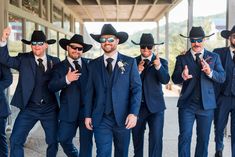 a group of men in suits and hats posing for the camera with their fingers up