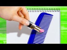 a person holding a pen and writing on a piece of paper next to a blue comb