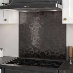 a black stove top oven sitting inside of a kitchen next to white cabinets and drawers