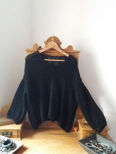 a black sweater is hanging on a wooden rack