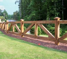 a wooden fence is shown in front of some grass and trees on the other side