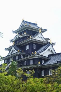 a tall black and white building surrounded by trees