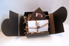 an open gift box with a football and bat design on the front, tied in brown paper