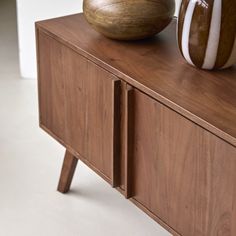 two vases sitting on top of a wooden cabinet