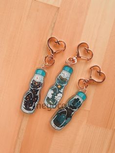 three bottle shaped key chains sitting on top of a wooden floor