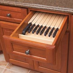 an open drawer with knives in it on top of a kitchen counter next to a sink