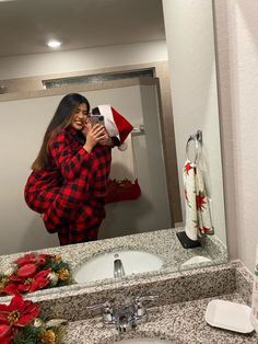 a woman taking a selfie in front of a bathroom mirror with christmas decorations on the counter