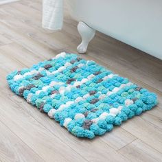 a blue and white rug sitting on top of a wooden floor next to a bath tub