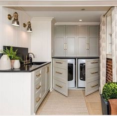 an open kitchen with white cabinets and black counter tops, along with potted plants