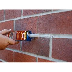 a person is spraying water onto a brick wall with a spray bottle in their hand