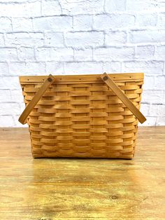 a wooden basket sitting on top of a table next to a white brick wall in the background