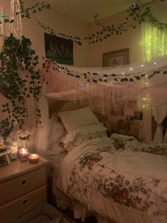 an unmade bed in a bedroom with plants hanging from the ceiling and candles lit on the floor