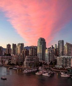 a city skyline with boats in the water at sunset