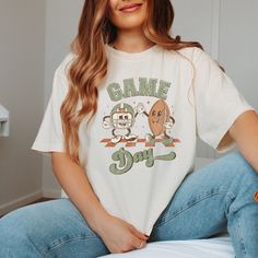 Hey there, football fan! Are you ready to add some retro flair to your game day wardrobe? Our "Game Day Football Friends" Comfort Color Tee is perfect for you. Featuring fun, retro characters, this tee brings a nostalgic touch to your football celebrations. Crafted from ultra-soft, high-quality cotton, our "Game Day Football Friends" Tee showcases a lively design of retro football characters. Utilizing state-of-the-art DTG printing technology, this tee ensures long-lasting colors and durability, Football Friends, Football Celebrations, Football Spirit, Game Day Football, Friends Tee, Retro Football, Games To Buy, Sports Tees, Comfort Colors Tee