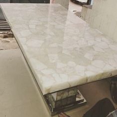 a man standing next to a counter top in a kitchen with white tiles on it