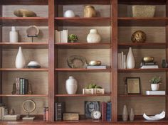 a wooden bookcase filled with lots of books and vases on top of it