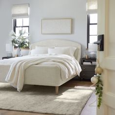 a white bed sitting in a bedroom next to a window