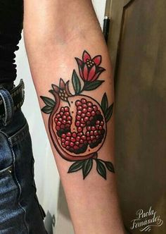 a tattoo with pomegranates and leaves on the arm that has a skull in it