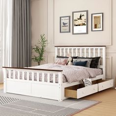 a white bed with drawers underneath it in a room next to a window and rug