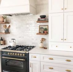 a stove top oven sitting inside of a kitchen next to white cupboards and shelves