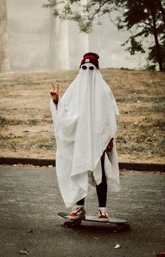 a man dressed as a ghost riding a skateboard