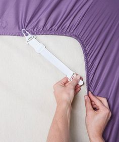 a person is holding an electronic device in their hand while laying on a bed with purple sheets