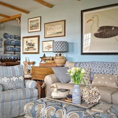 a living room filled with blue and white furniture next to a painting on the wall