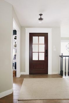 an empty entryway with a brown door and white walls