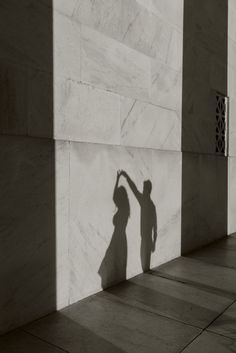 a shadow of a person reaching up to the side of a building