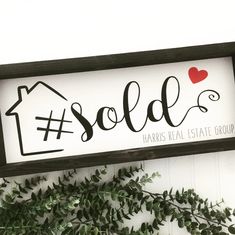 a sign that says sold hanging from the side of a wall next to a plant