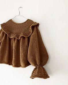 a brown sweater hanging on a white wall