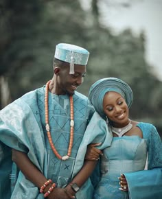 two people standing next to each other with beads on their heads and wearing blue outfits