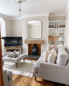 a living room filled with furniture and a fire place under a mirror on the wall