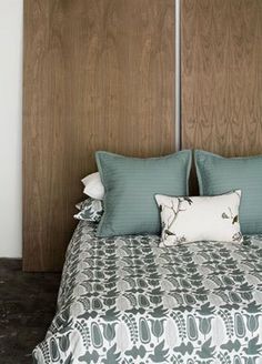 a bed with blue and white pillows on top of it next to a wooden headboard