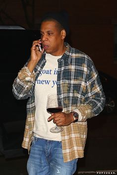 a man talking on a cell phone while holding a glass of wine in his hand