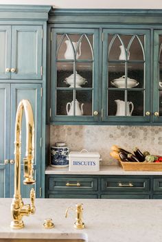 a kitchen with blue cabinets and gold faucets