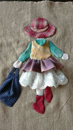 the doll is wearing a hat, dress and boots with two purses next to it