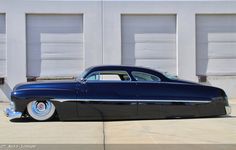 a classic car parked in front of two garage doors