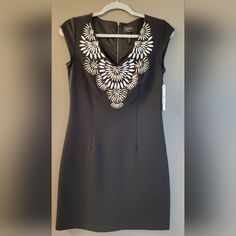 This Is An Absolutely Stunning Little Black Dress With Beautiful Embroidery And Gold-Tone Embellishments At The V-Neckline. The Dress Is Lined And Has A Zipper On The Back. It Would Be Perfect For Cocktail Parties Or Slightly More Formal Events. New, Never Worn. Comes With Tags And 4 Extra Studs. Measurements Bust: 16" Waist: 14.5" Hip: 17" Length: 33" Shoulder To Hem Zipper Length: Approx. 21" Size: 4 Us Color: Black Material: 70% Rayon / 27% Nylon / 3% Spandex | Lining: 100% Polyester Fitted V-neck Dress With Embroidered Neckline, Embroidered V-neck Dress, Fitted Embroidered V-neck Dress, V-neck Embroidered Dress With Embroidered Neckline, Fitted Sleeveless Dress With Embroidered Neckline, Elegant V-neck Dress With Embroidered Neckline, Fitted V-neck Embroidered Dress With Floral Details, Formal Embroidered V-neck Dress, Fitted Embroidered Dress With V-neck