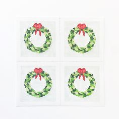 four cross stitch christmas wreaths on white paper