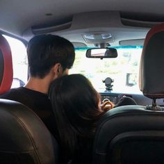 a man and woman sitting in the back seat of a car looking at each other