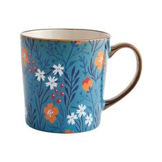 a blue mug with orange, white and blue flowers on it's rim is shown