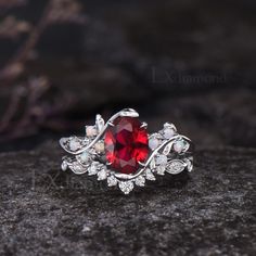 a red ring sitting on top of a black stone covered in white crystals and surrounded by leaves