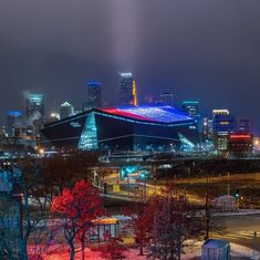 the stadium is lit up in red, white and blue with lights on it's roof