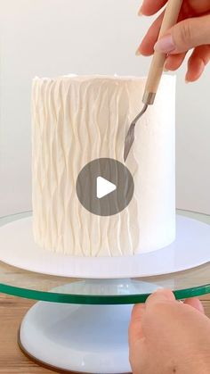 someone is decorating a cake with white icing